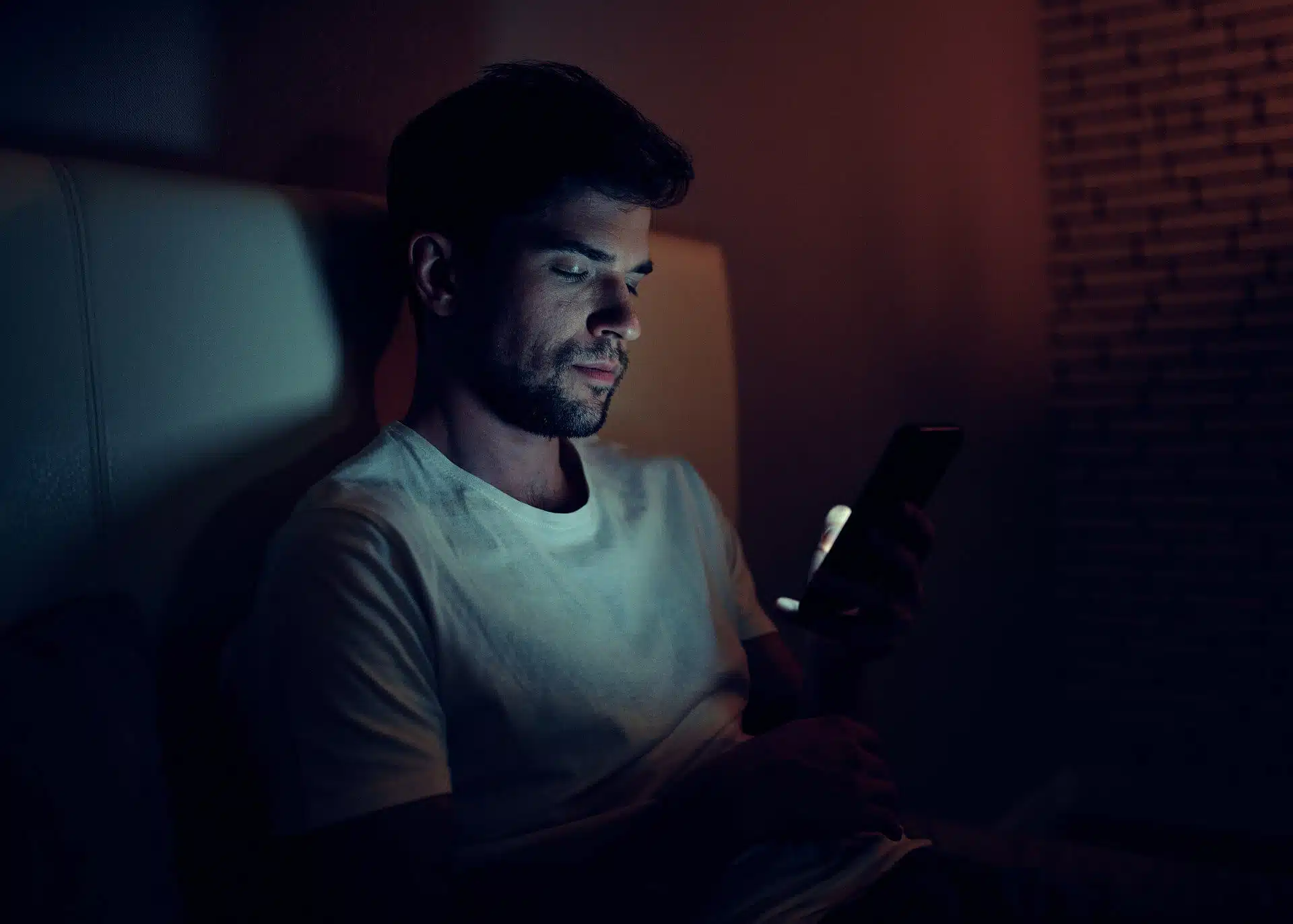 young man at night in bed looking at his phone