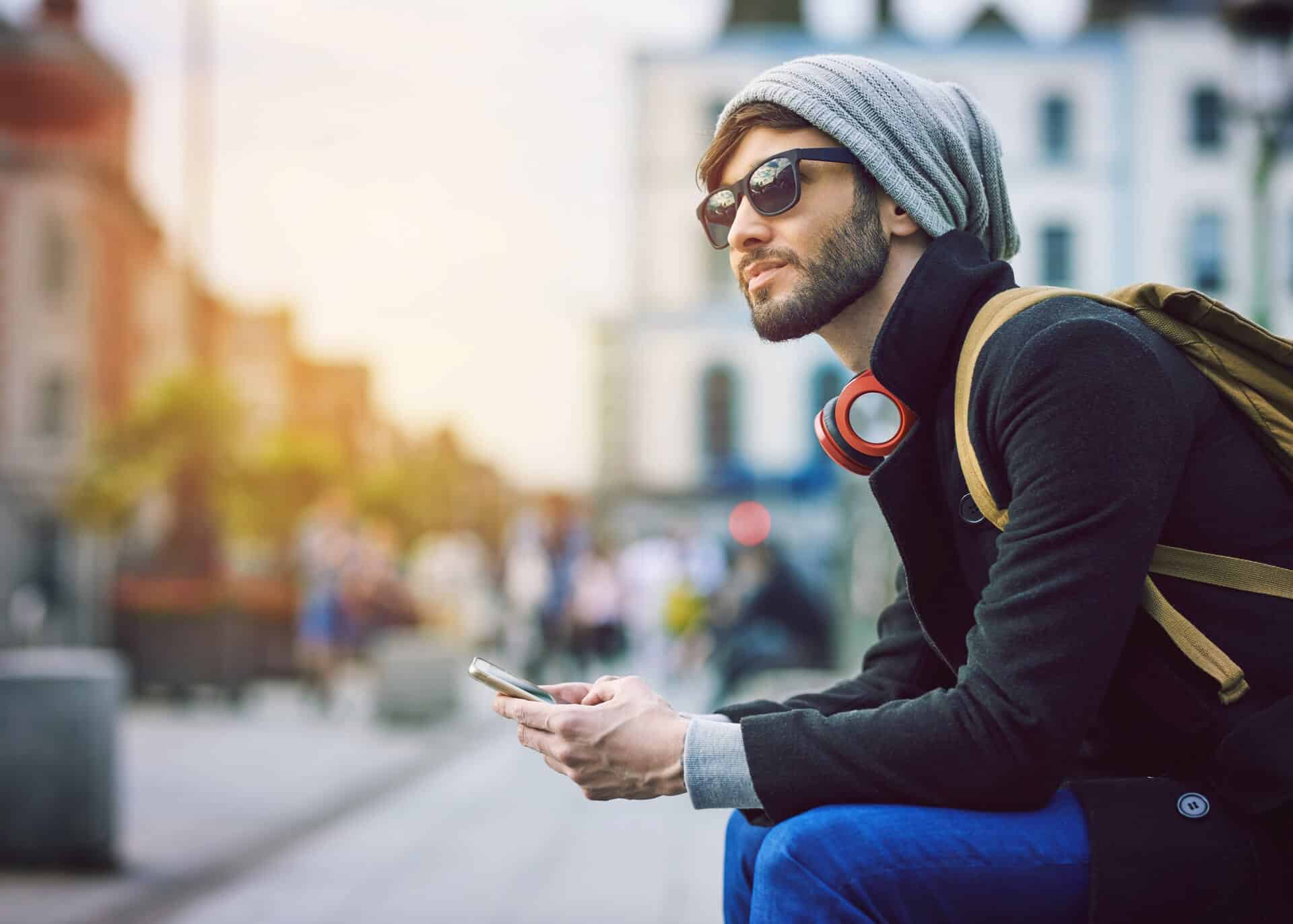 young man with phone thinking if he should stop texting a girl