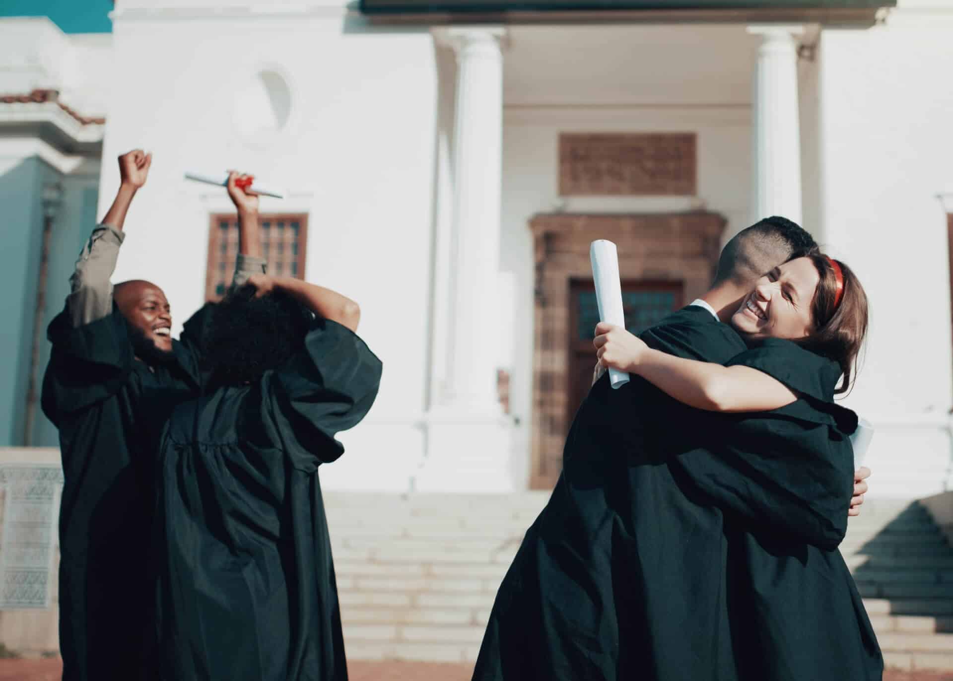 students hugging celebrating graduation