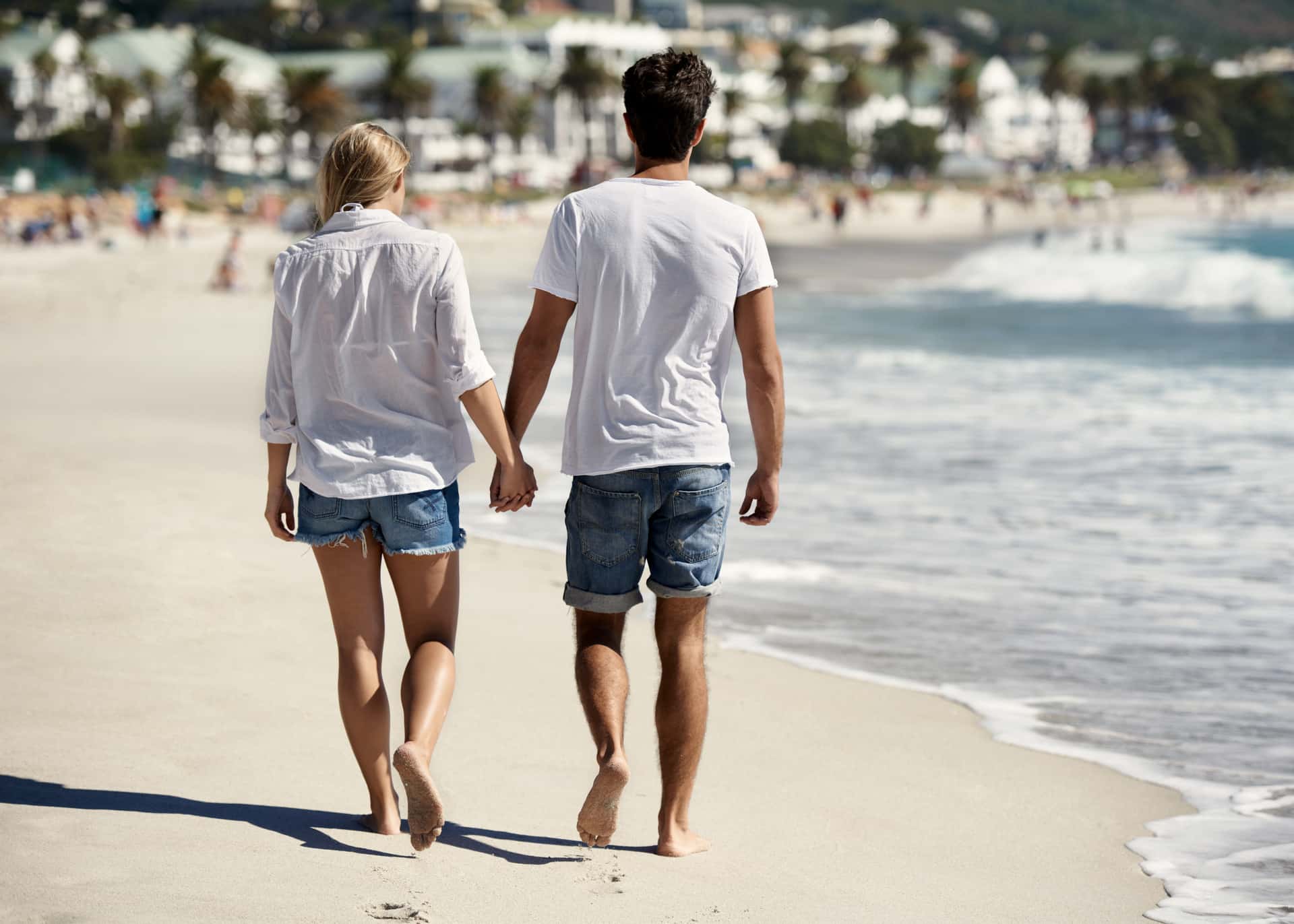 back view of a couple walking on the beach holding hands