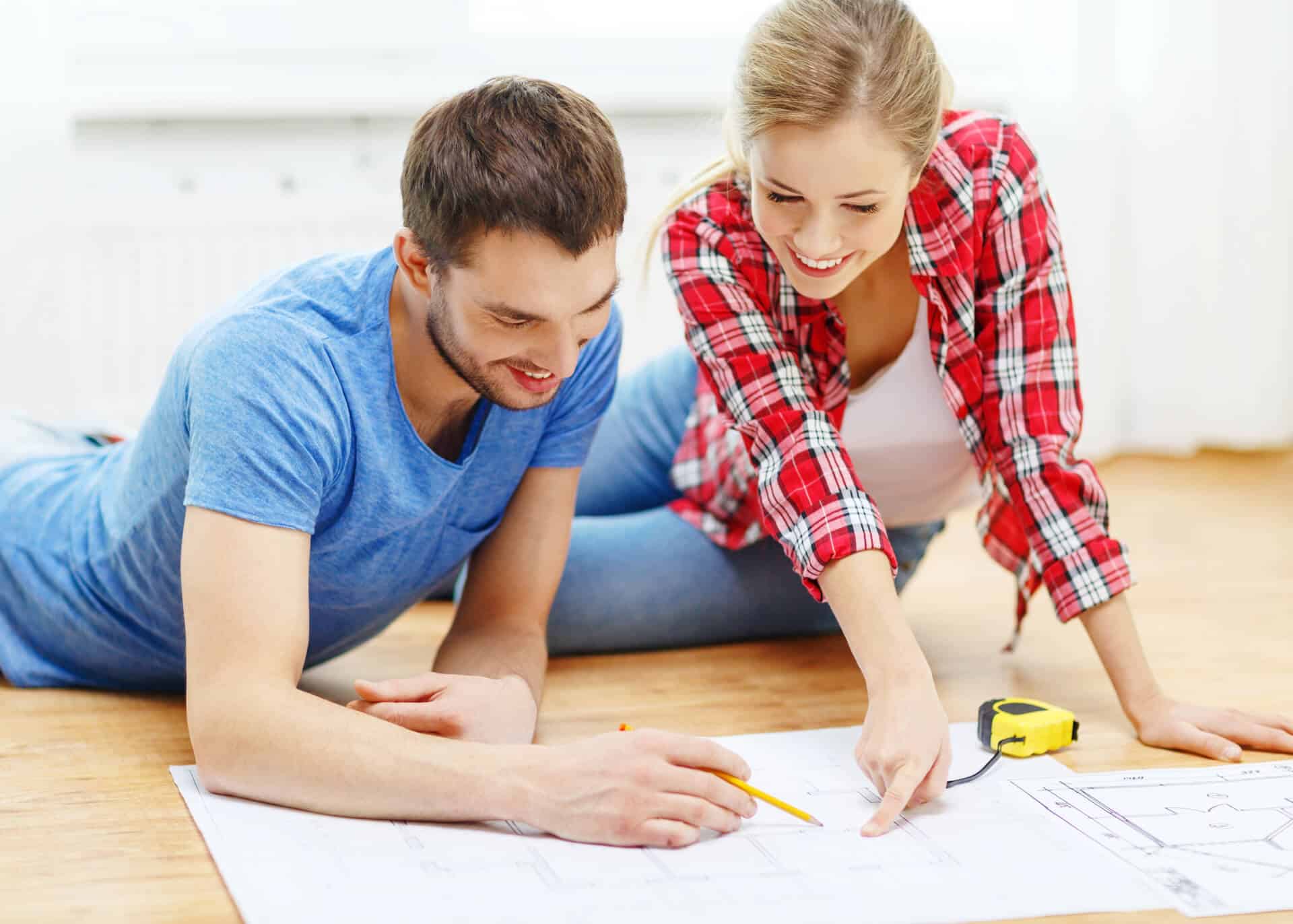 smiling couple looking at blueprint of house