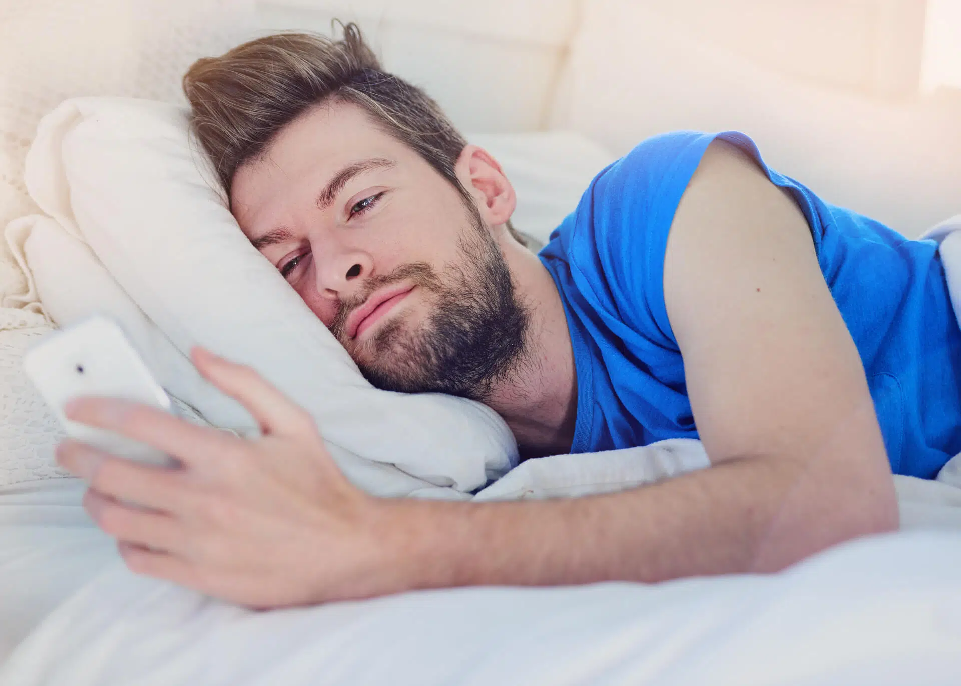 man in bed texting his girlfriend in the morning
