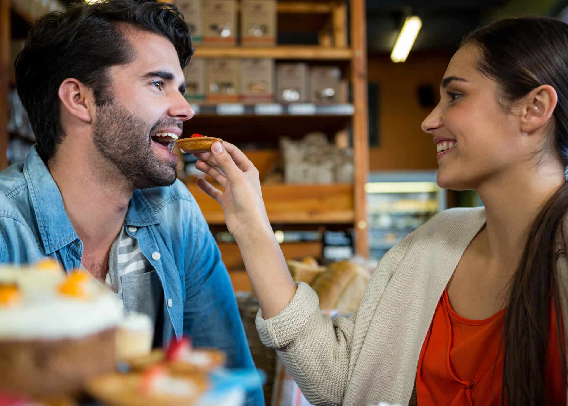 happy woman feeding man with cookie