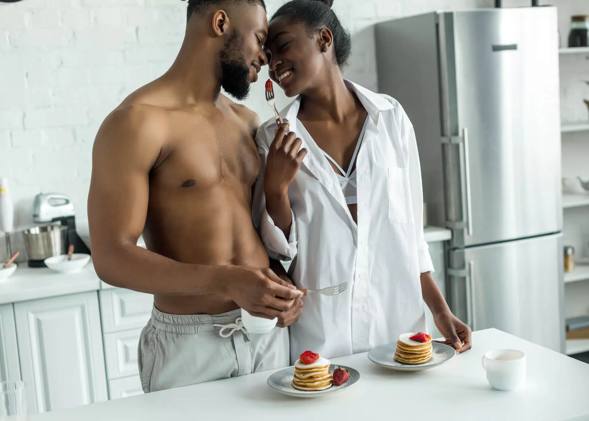 young couple teasing each other with food in the kitchen