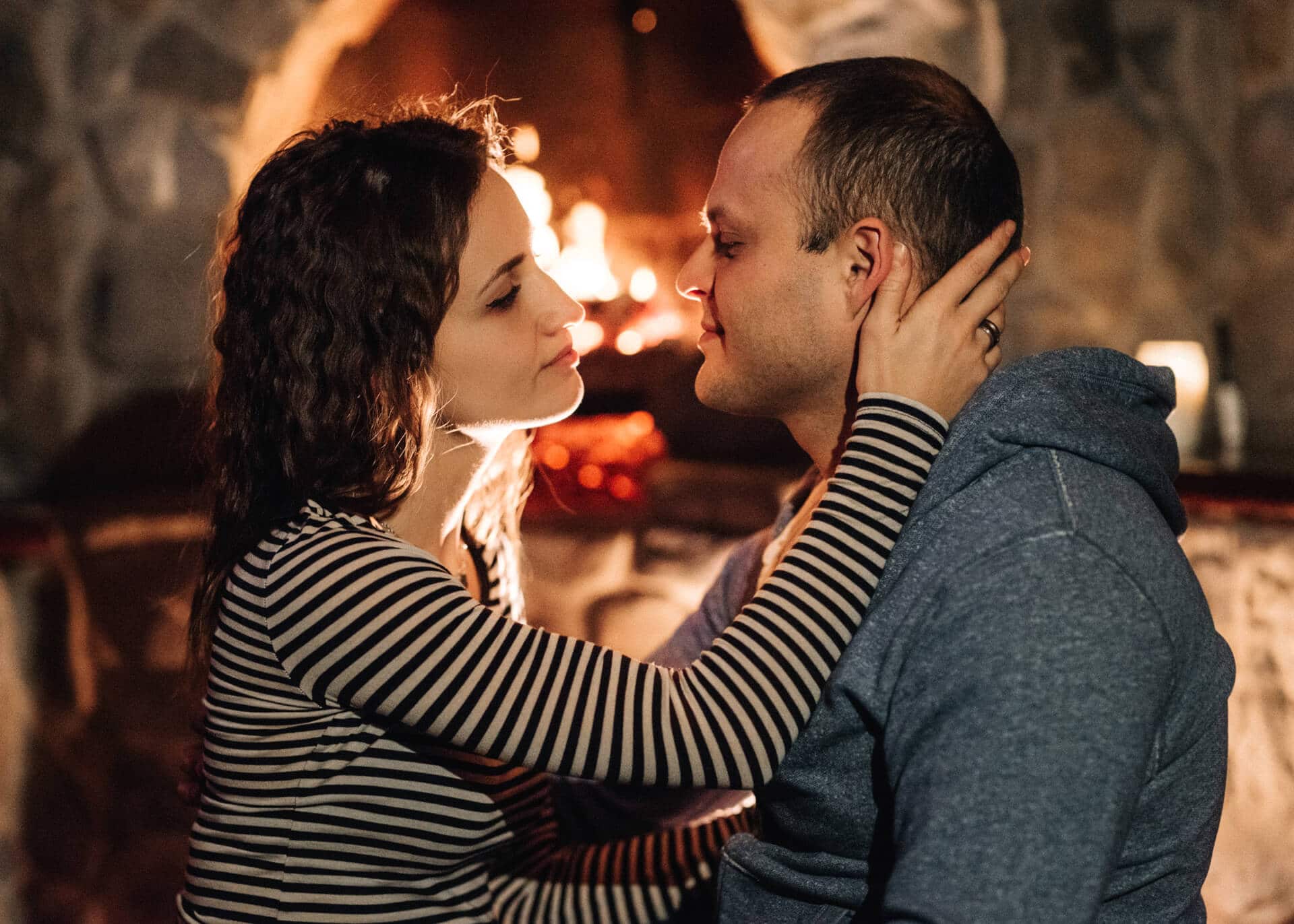 guy and girl are sitting at burning fireplace