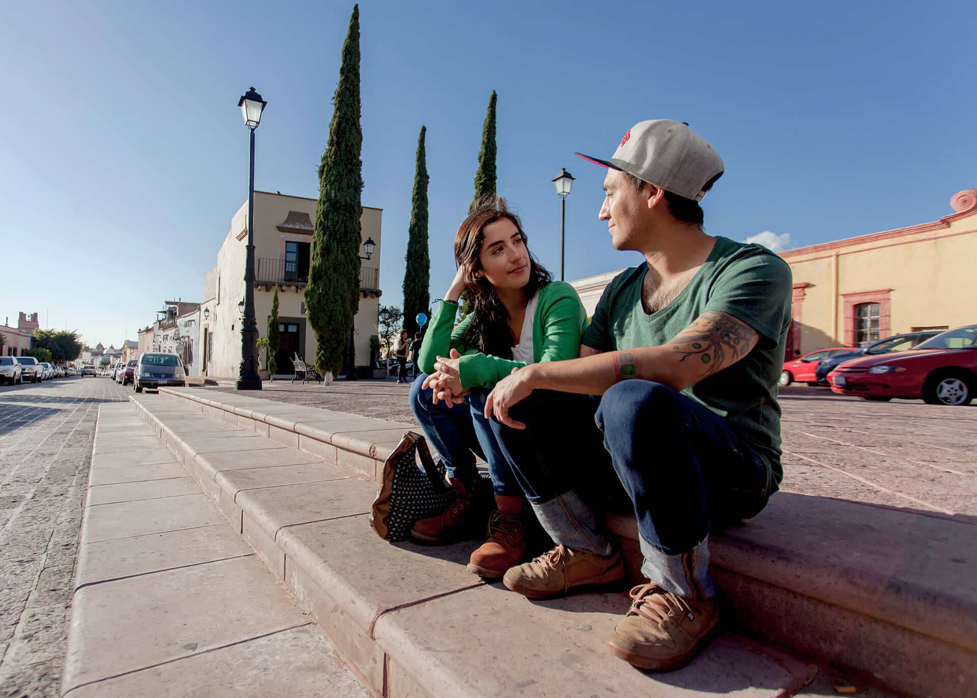 young couple sitting on a curb chatting