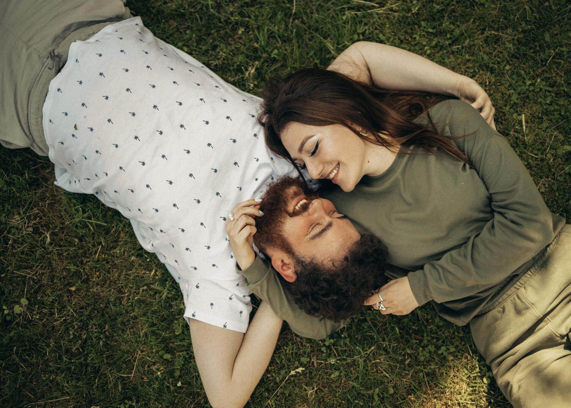 man and woman in love laying on the grass