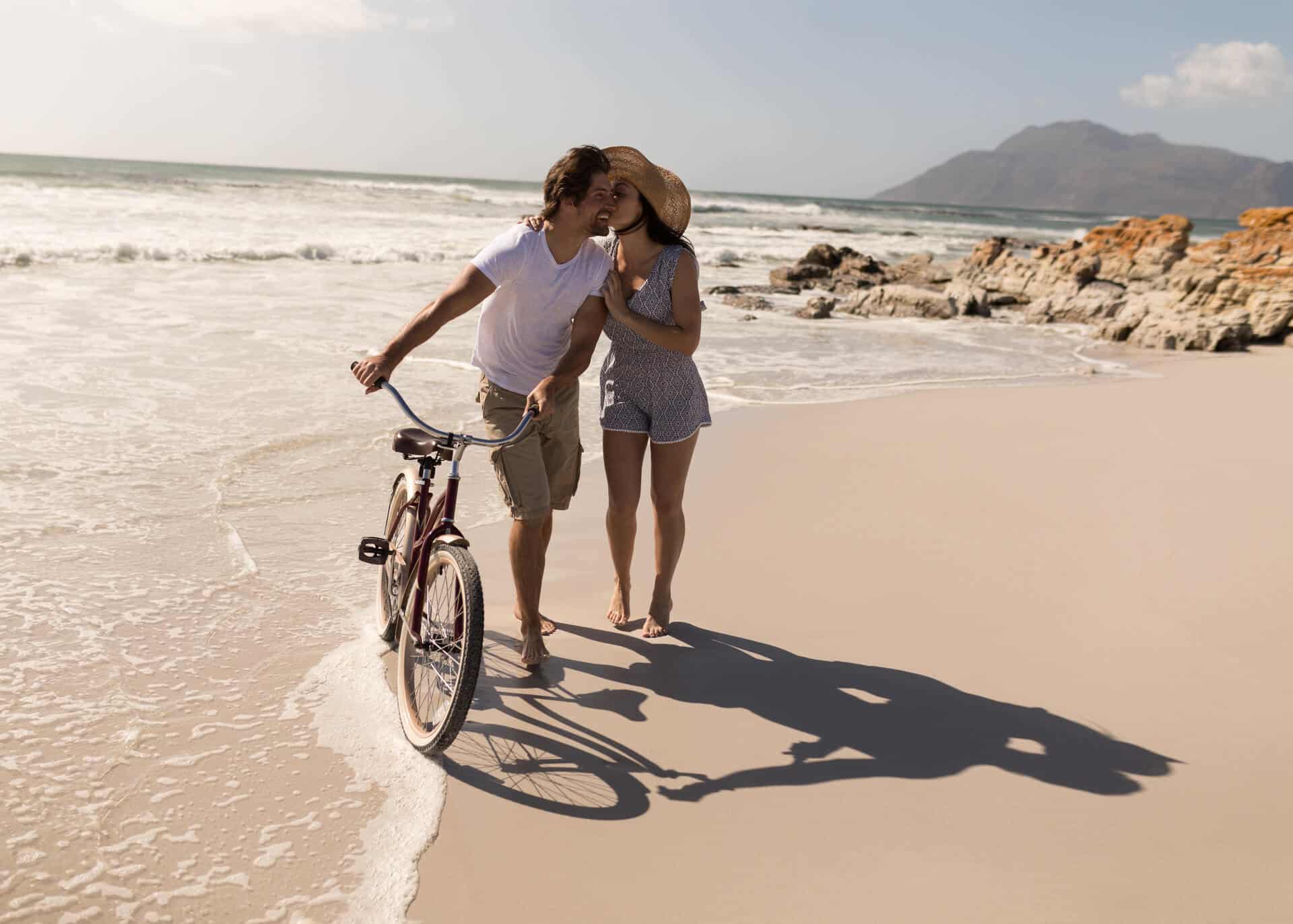 young couple with bike kissing on the beach
