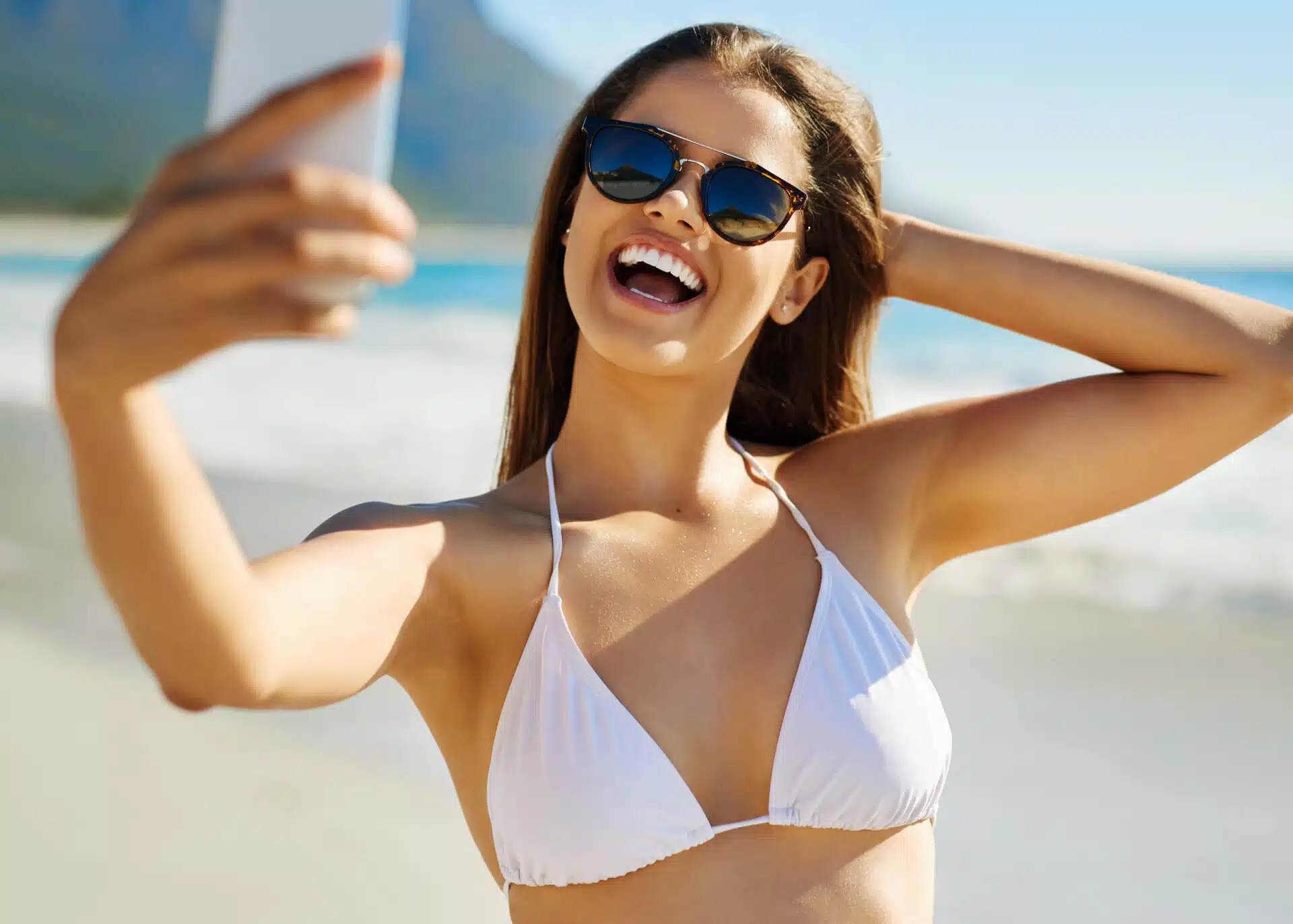 young woman taking selfie on the beach