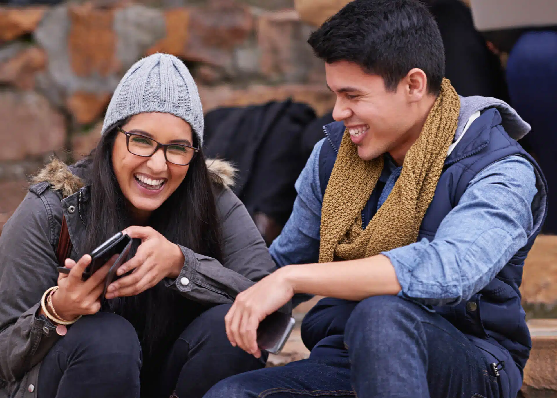 young couple laughing together holding their phones