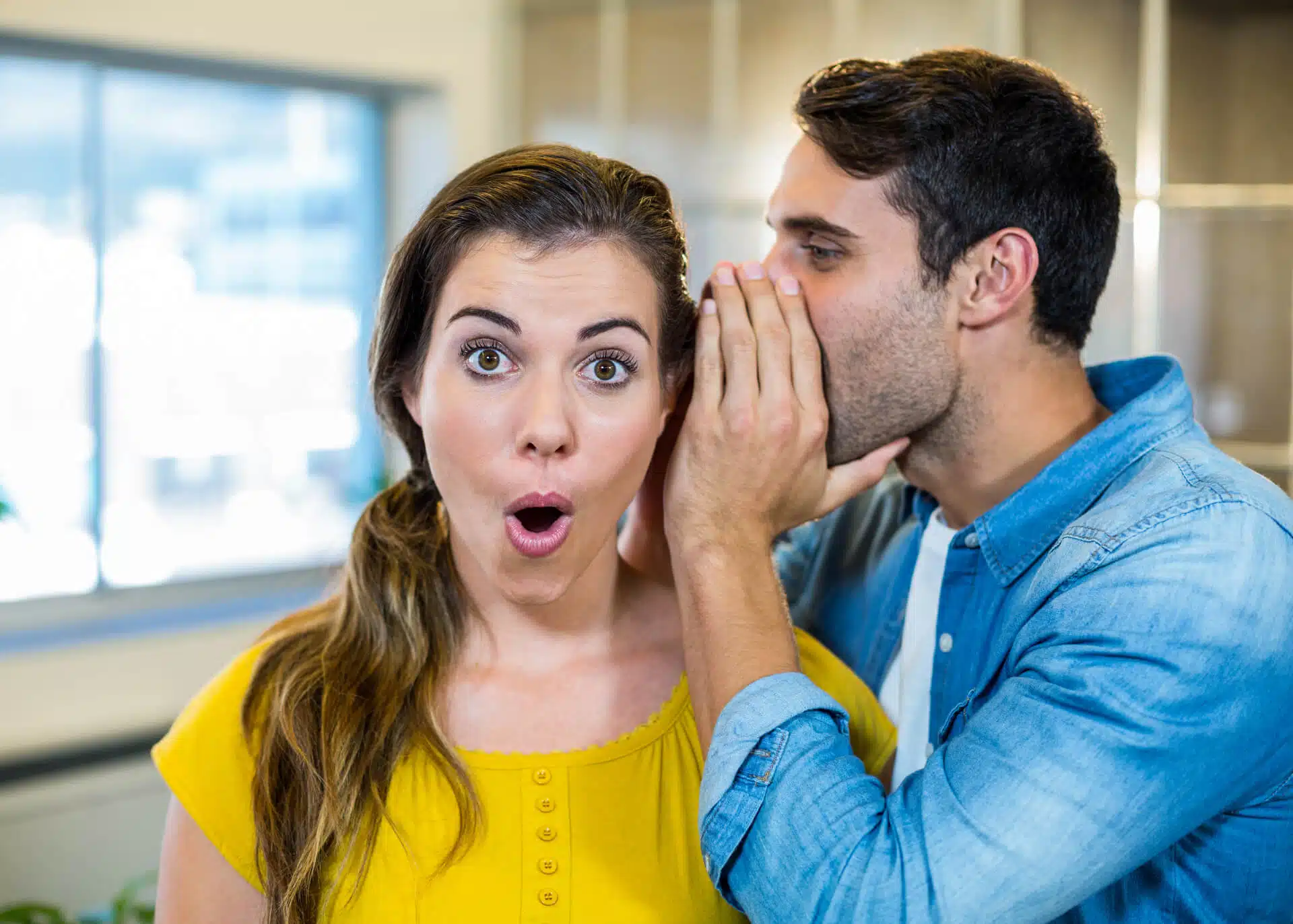 man whispering a secret into womans ear