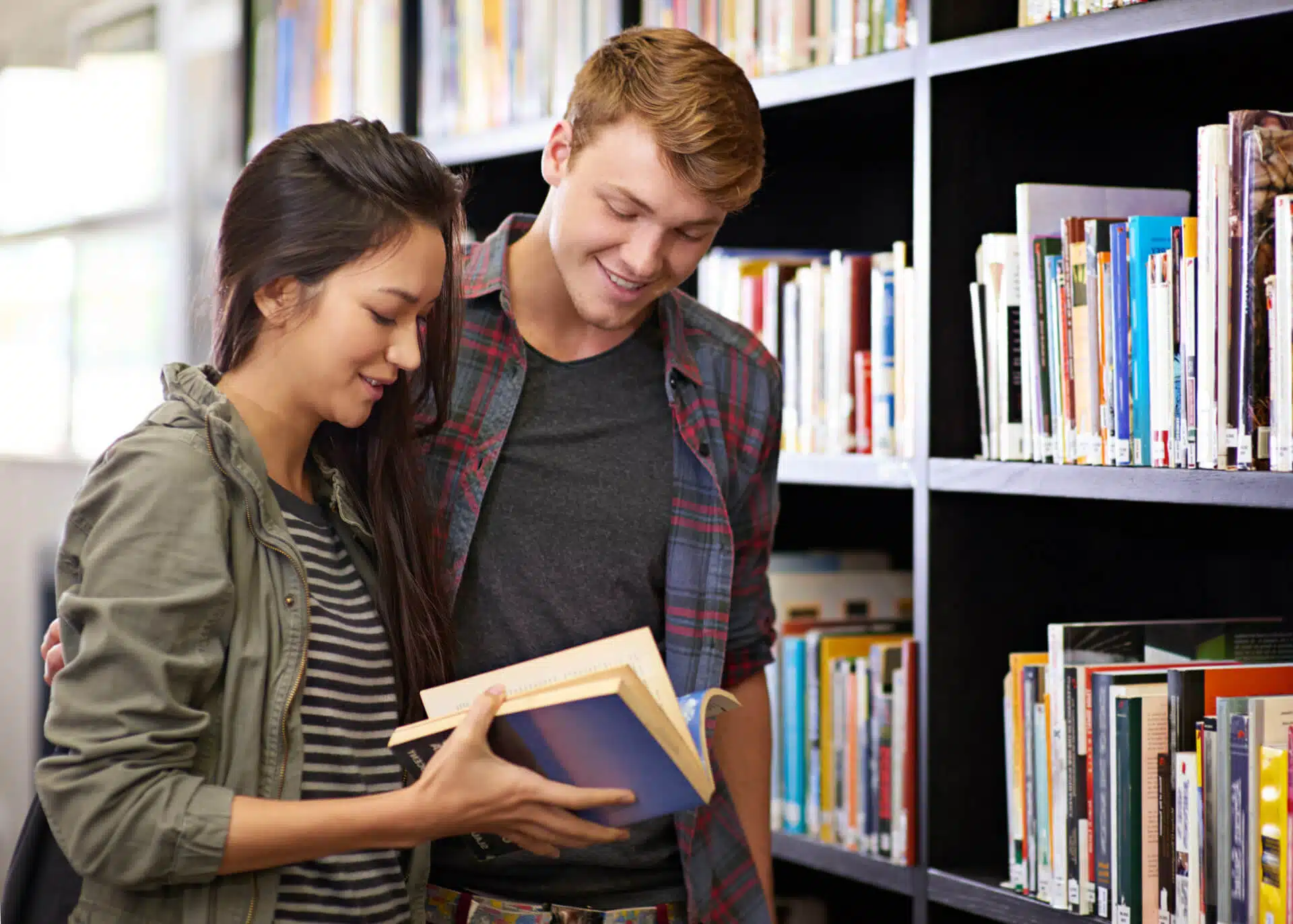 young couple flicking a book in a library