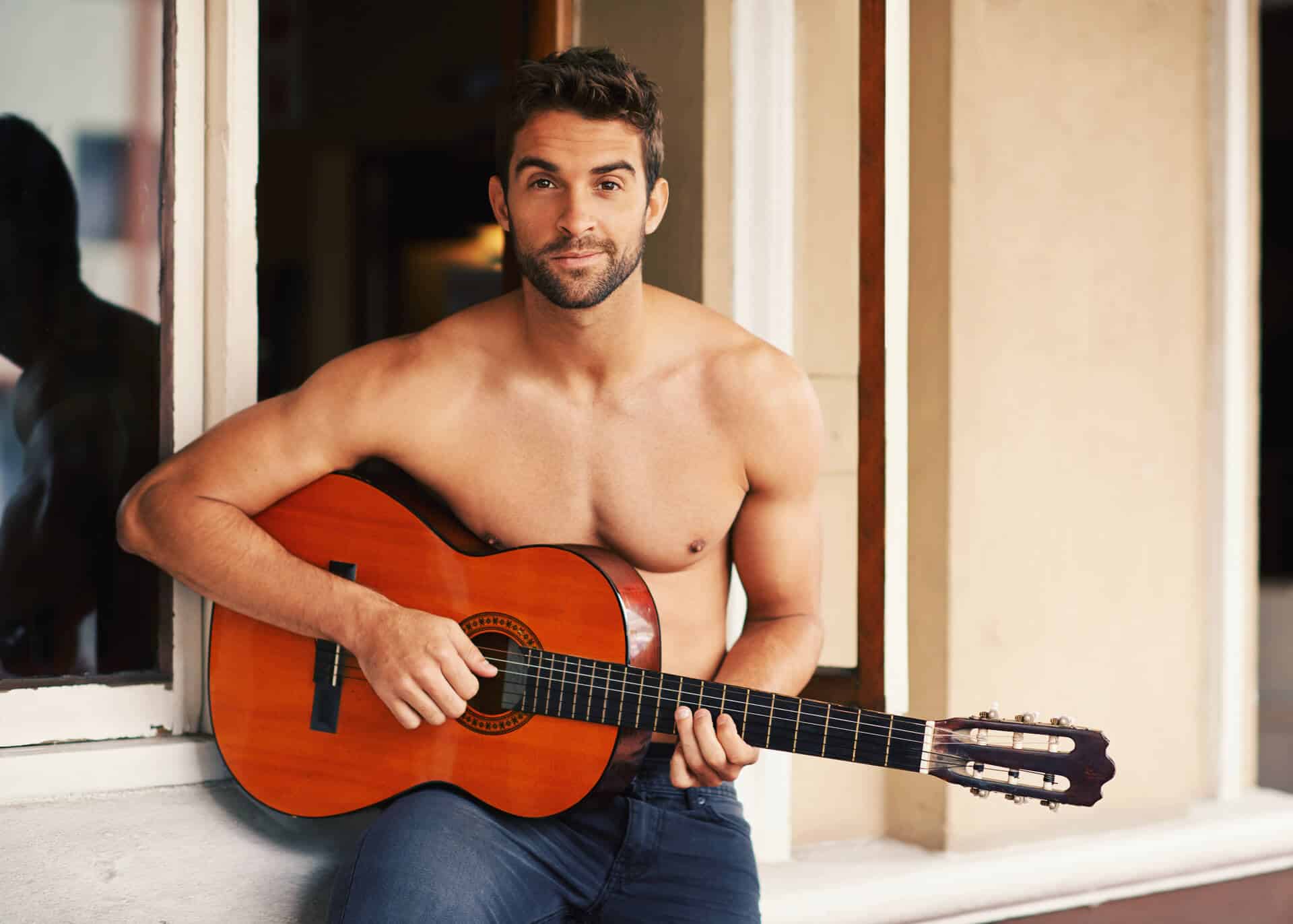 shirtless young man playing guitar