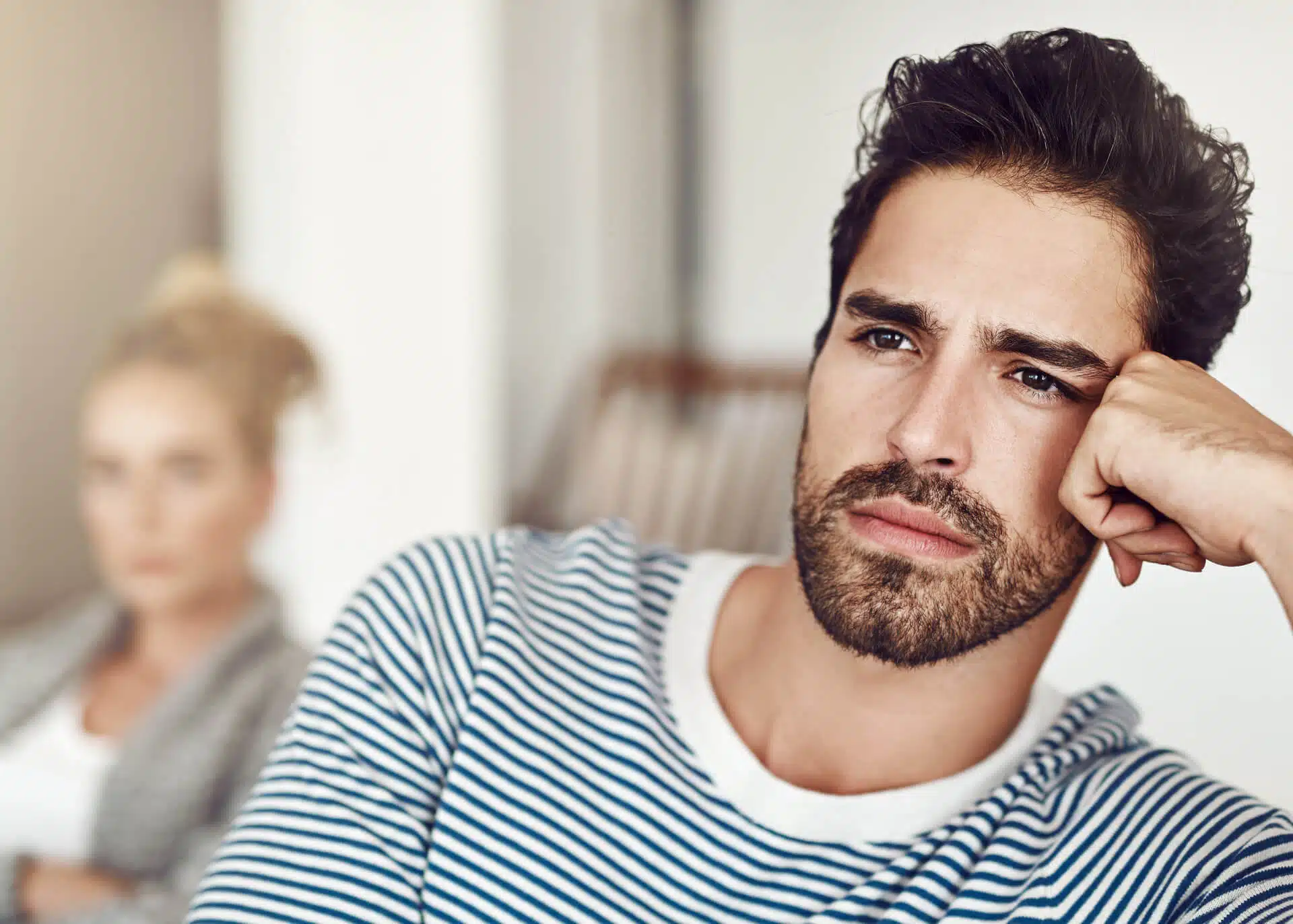 unhappy man with woman in the background