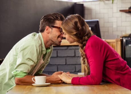young couple about to kiss in a cafe